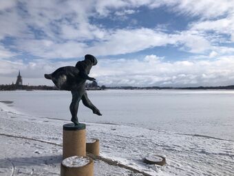 Eine Skulptur am Rande eines schneebedeckten Sees.