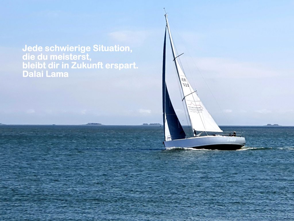 Foto eines kleinen Segelbootes auf dem Wasser, im blauen Himmel steht der Satz "Jede schwierige Situation, die du meisterst, bleibt dir in Zukunft erspart. Dalai Lama"